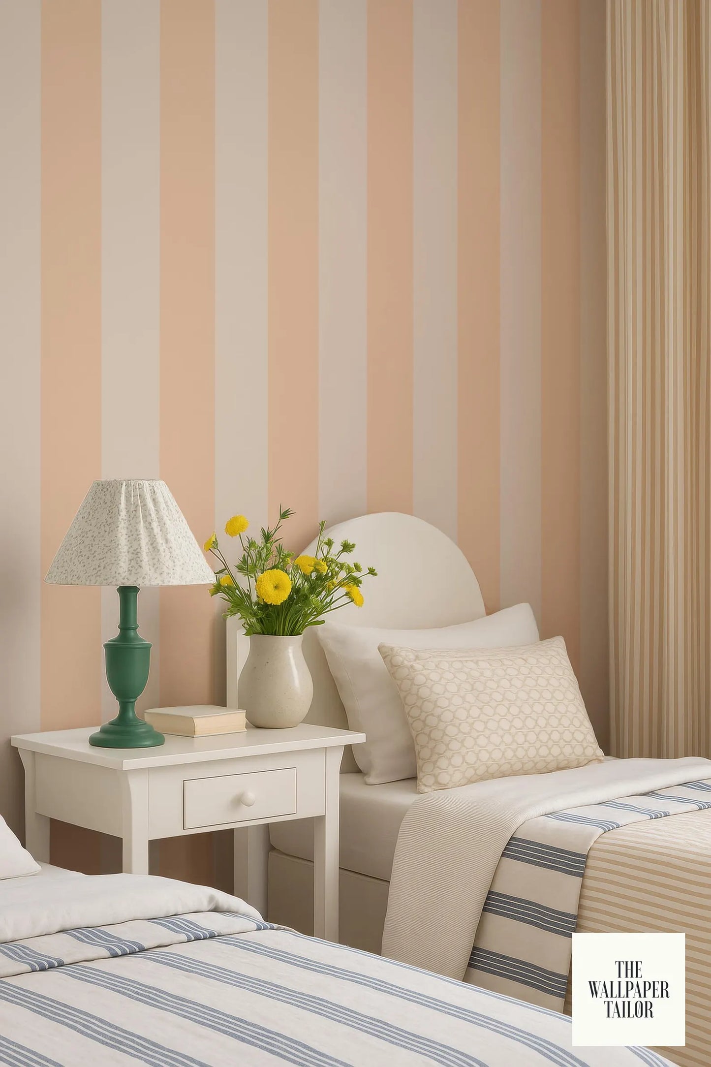 a cozy bedroom with a white bed, a nightstand with a lamp and a vase of yellow flowers, and striped wallpaper.