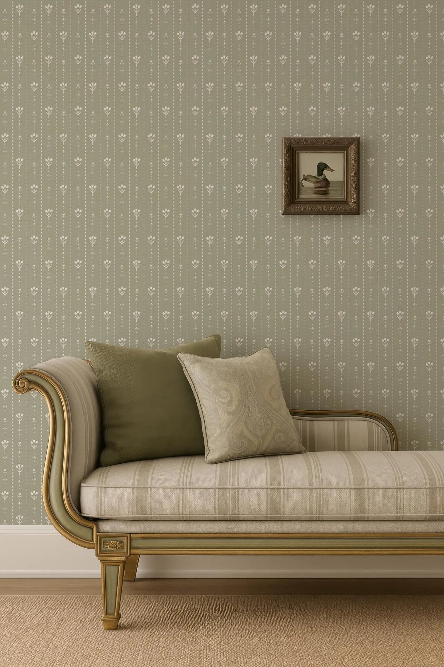 a beige sofa with a gold frame, placed against a wall with a floral wallpaper. A framed picture of a duck is hanging on the wall above the sofa.