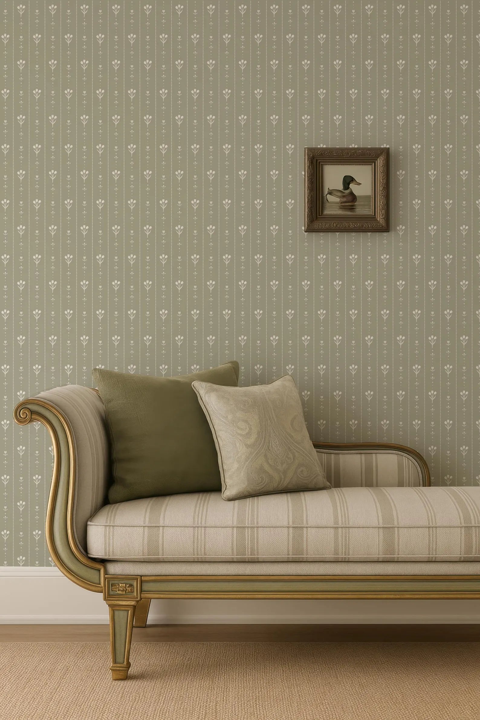 a beige sofa with a gold frame, placed against a wall with a floral wallpaper. A framed picture of a duck is hanging on the wall above the sofa.