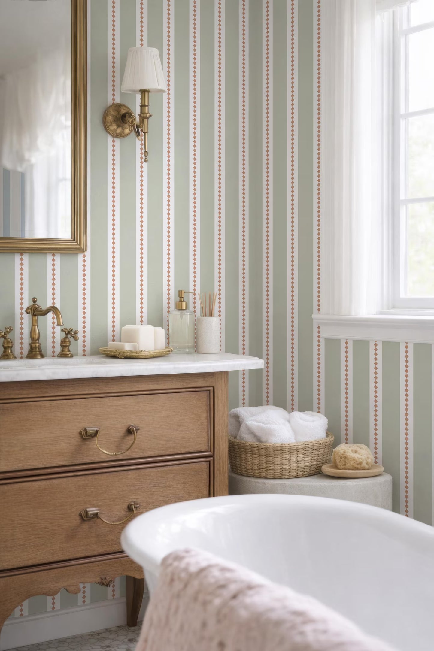 a bathroom with a white bathtub, a wooden dresser, and a mirror. The walls are covered in green and white striped wallpaper, and there is a window in the background.