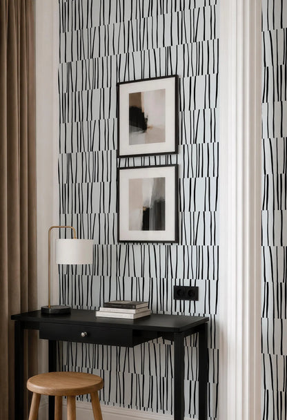 a modern black and white desk with a lamp, a stack of books, and a framed abstract artwork on the wall above it.