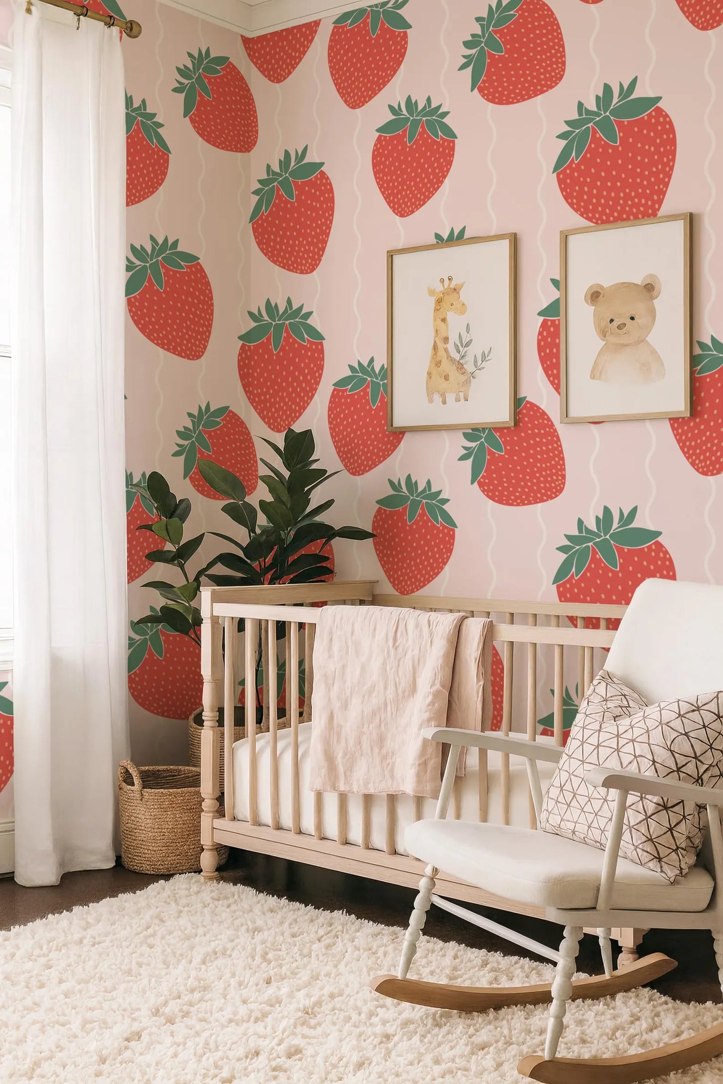 a nursery room with a white crib, a white rocking chair, and a wall covered in a strawberry wallpaper. There is also a potted plant and a basket in the room.