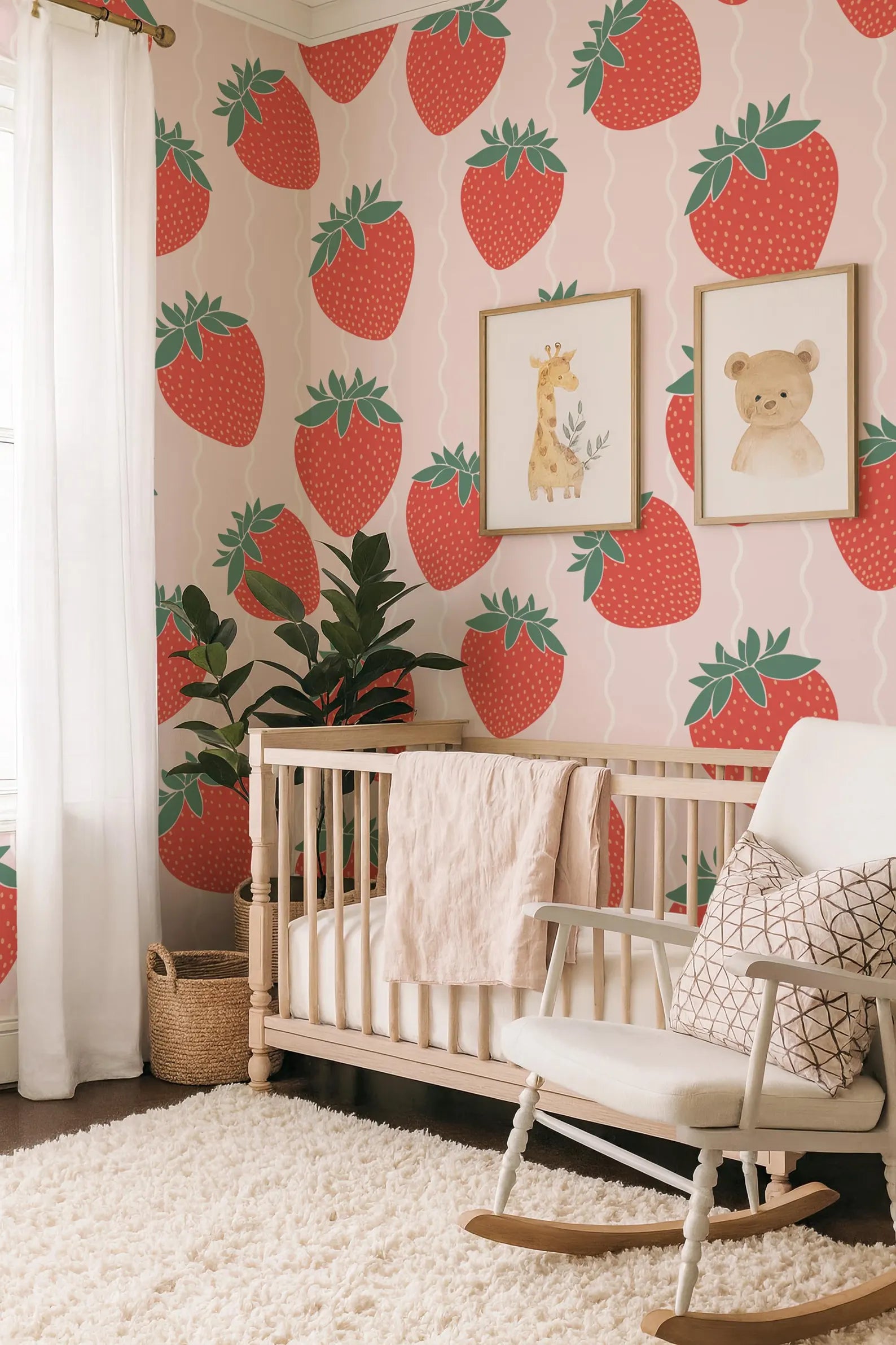 a nursery room with a white crib, a white rocking chair, and a wall covered in a strawberry wallpaper. There is also a potted plant and a basket in the room.