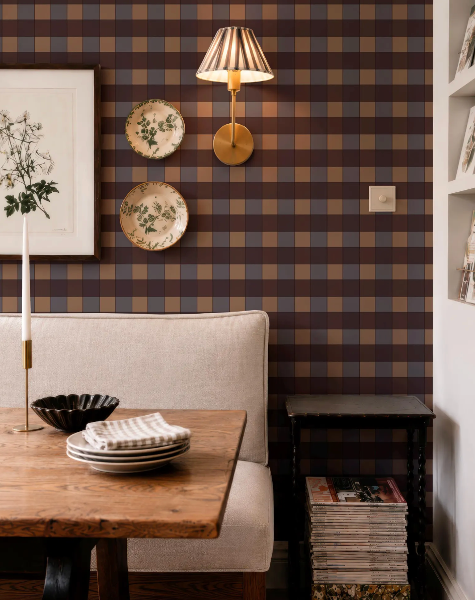a cozy dining area with a wooden table, a white sofa, and a lamp. The wall behind the table has a checkered pattern, and there are two plates and a bowl on the table. The overall scene has a warm and inviting atmosphere.