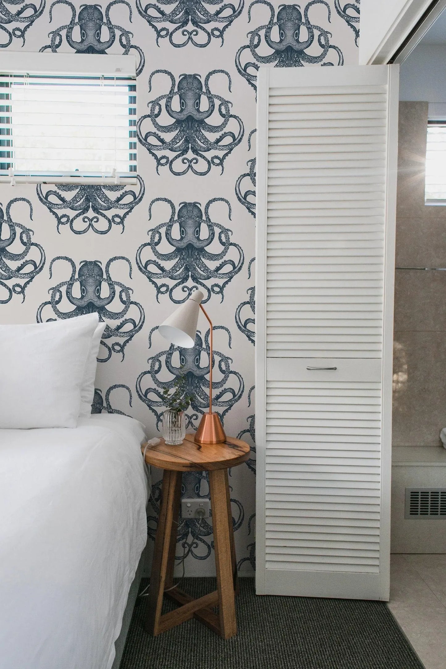 a bedroom with a bed, a nightstand, and a wallpapered wall with an octopus design.