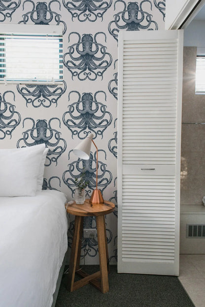 a bedroom with a bed, a nightstand, and a wallpapered wall with an octopus design.
