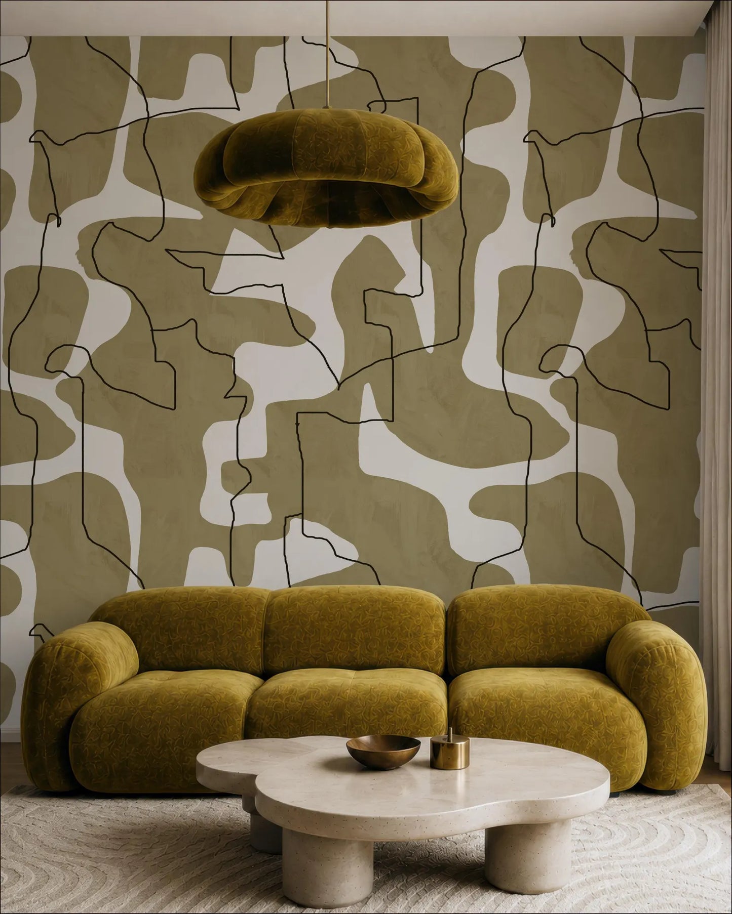 a modern living room with a large, plush yellow sofa and a round coffee table. The sofa is positioned in front of a wall with a bold, abstract pattern in shades of brown and white. A large, round light fixture hangs above the sofa, providing ample lighting to the space.