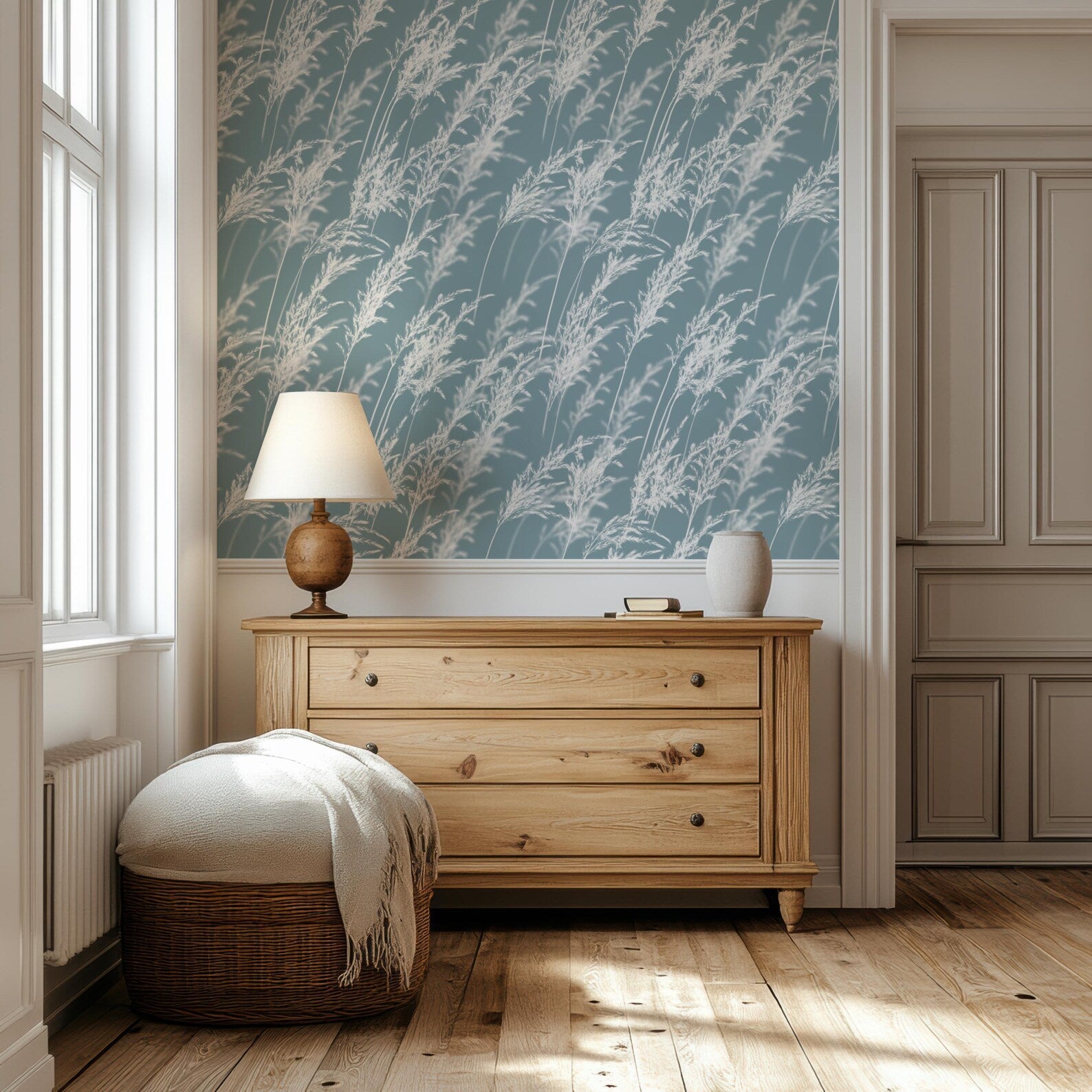 a cozy corner of a room with a wooden dresser, a lamp, and a woven ottoman. The room has a blue and white patterned wallpaper, and a door is visible on the right side.