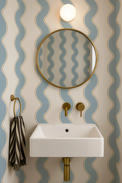 a bathroom with a white sink, a round mirror, and a striped towel. The walls are covered in blue and white wavy wallpaper, creating a modern and stylish atmosphere.