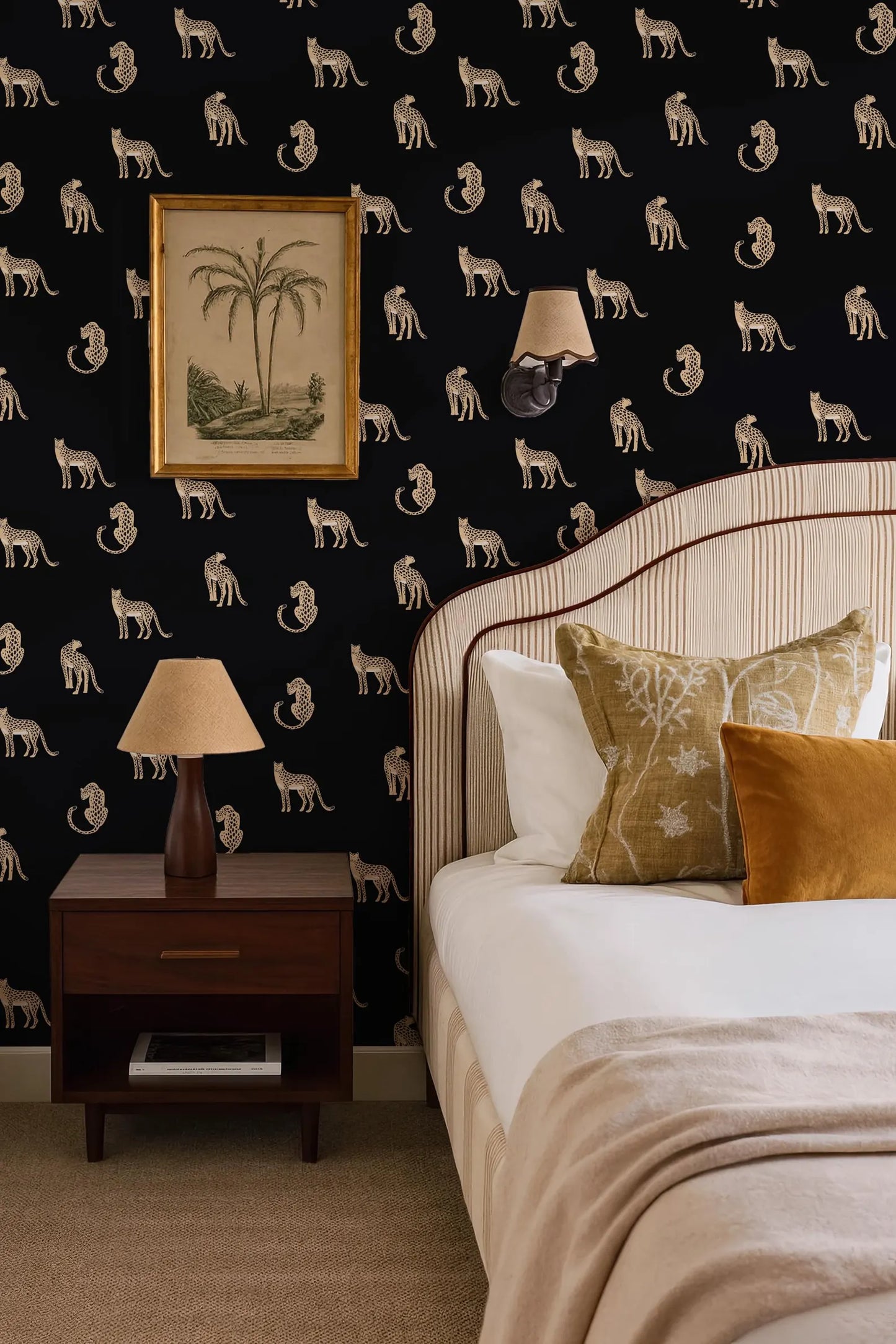 a bedroom with a black and white wallpaper pattern featuring a repeating design of cats. The room includes a bed with white linens, a wooden nightstand with a lamp, and a framed picture on the wall.