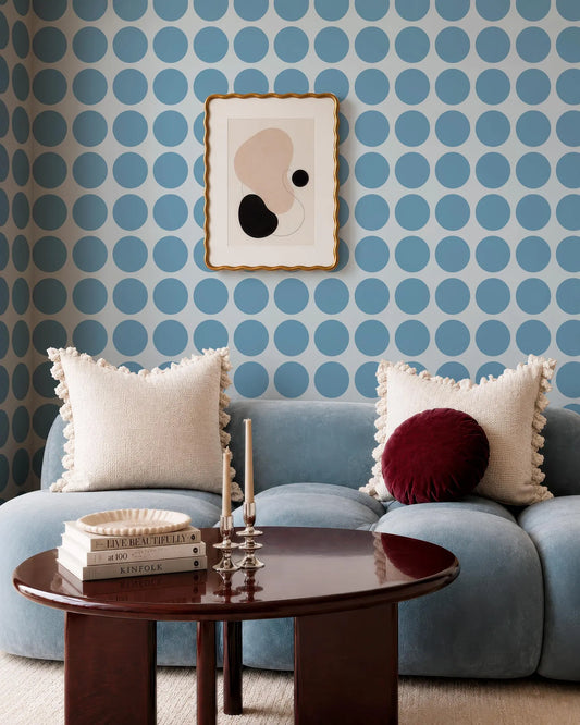 a cozy living room with a blue sofa adorned with two throw pillows, a wooden coffee table, and a framed abstract artwork on the wall.