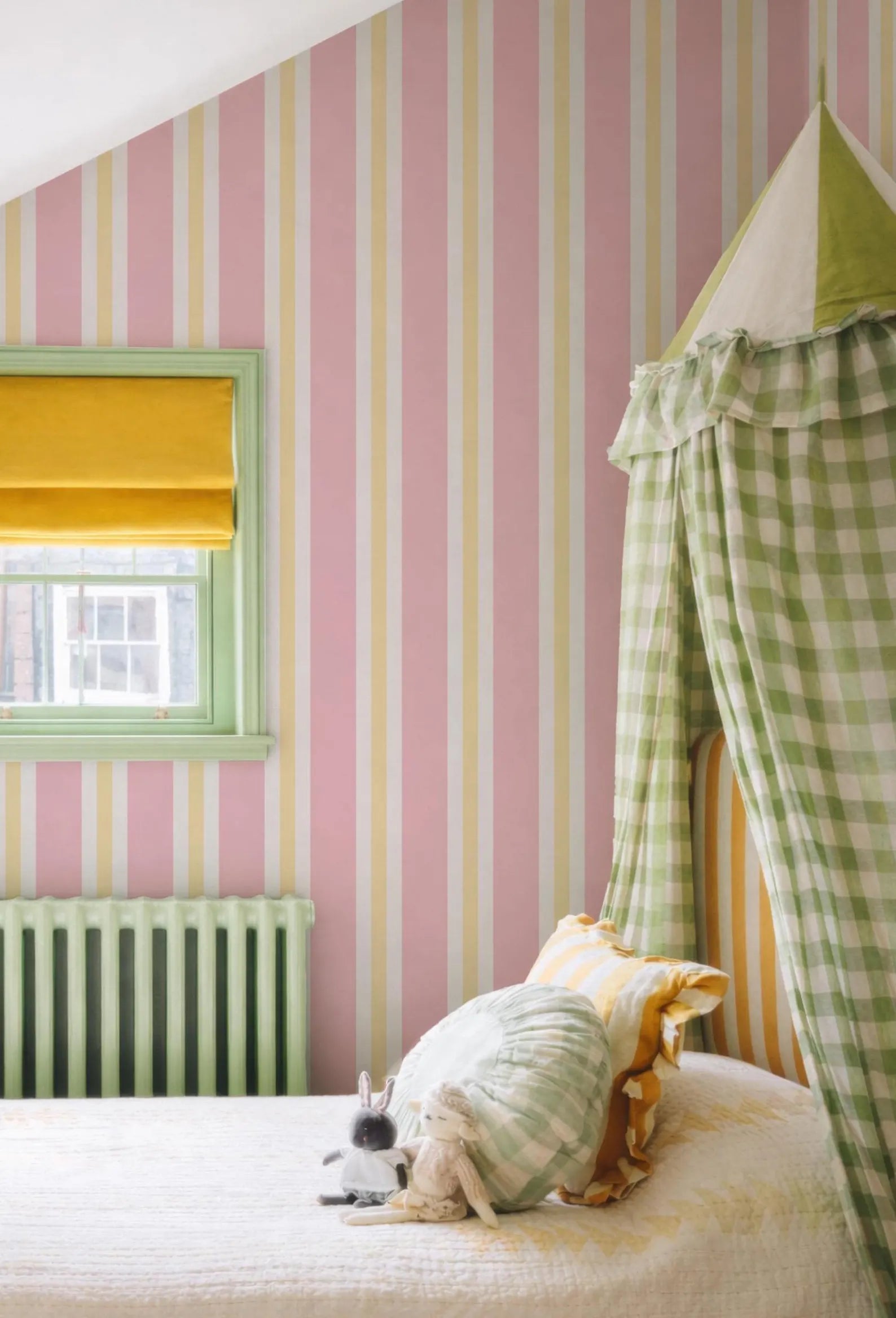 a cozy bedroom with a bed, a canopy, and a window with yellow curtains. The walls are covered in pink and yellow striped wallpaper, and there is a stuffed animal on the bed.