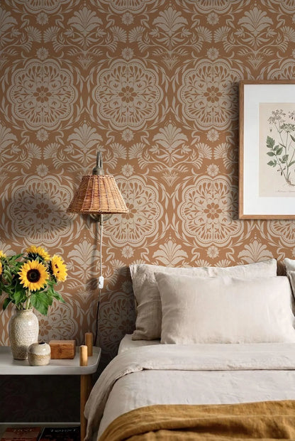 a cozy bedroom with a bed, a lamp, and a framed picture on the wall. The wall is covered in a patterned wallpaper, and the room has a warm, inviting atmosphere.