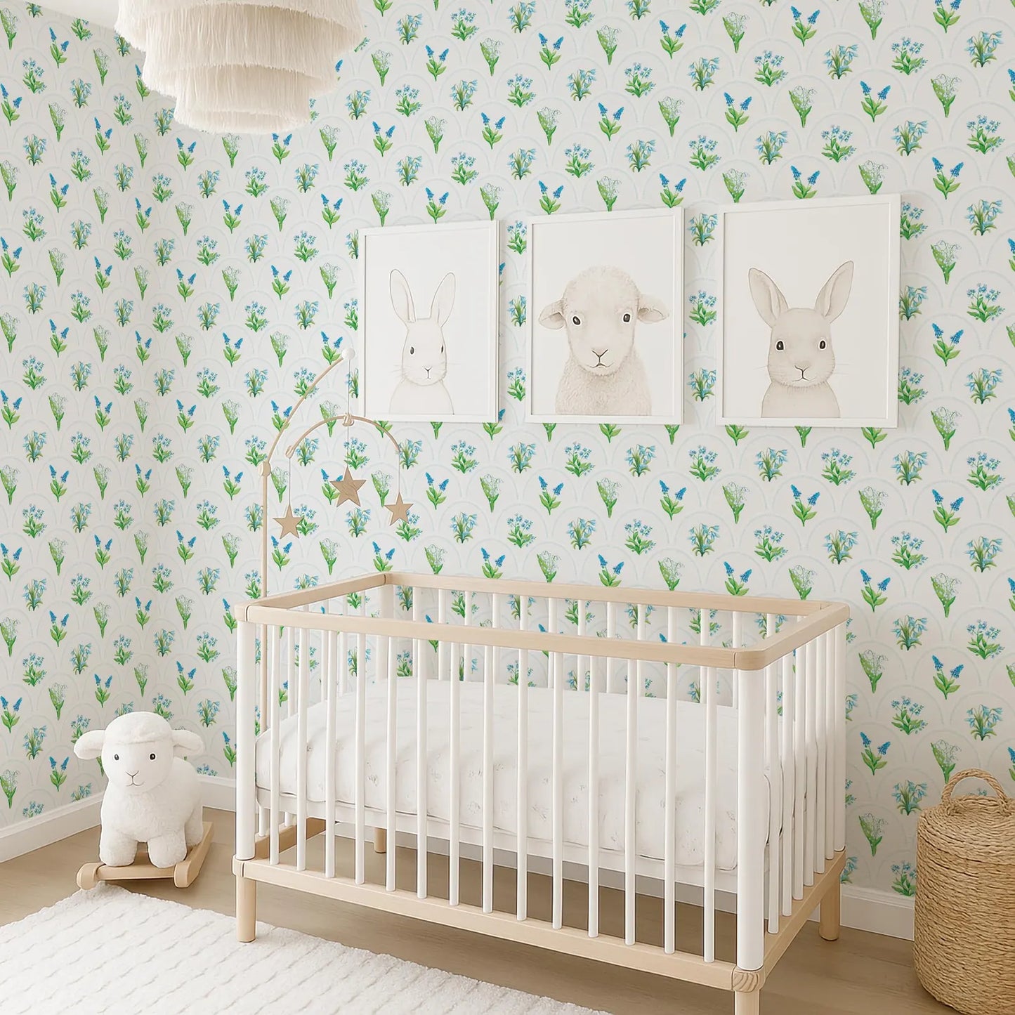 A nursery room with a white crib, a stuffed lamb, and three framed animal illustrations on the wall.