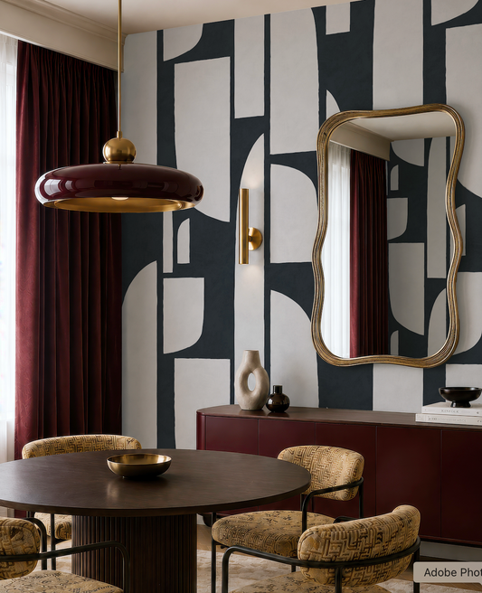 a modern dining room with a black and white geometric pattern on the wall, a round wooden table with a bowl on it, and a large mirror above the table.