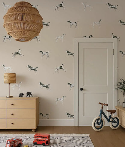 a room with a beige wall decorated with a pattern of black and white dogs. A wooden dresser with a lamp and a toy train are present in the room. A bicycle is also visible in the room.