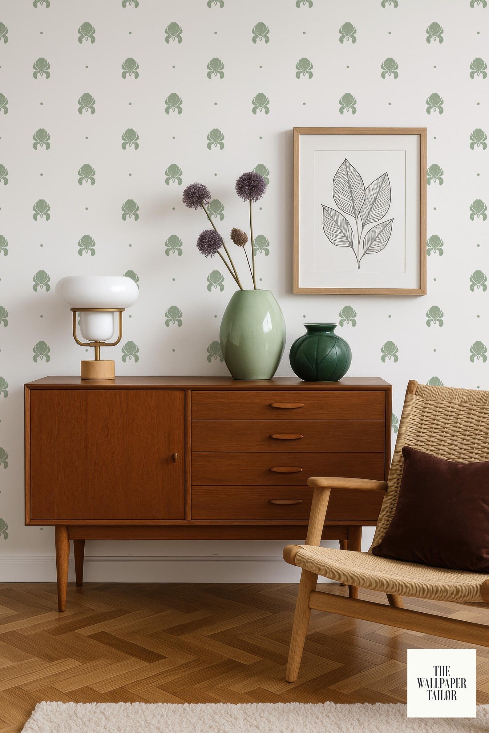 a cozy corner of a room with a wooden dresser, a woven chair, a framed picture, and a vase with purple flowers. The dresser has a wooden cabinet and drawers, and the chair has a woven seat. The framed picture is hanging on the wall, and the vase with purple flowers is placed on the dresser. The room has a warm and inviting atmosphere, with a touch of greenery from the flowers.