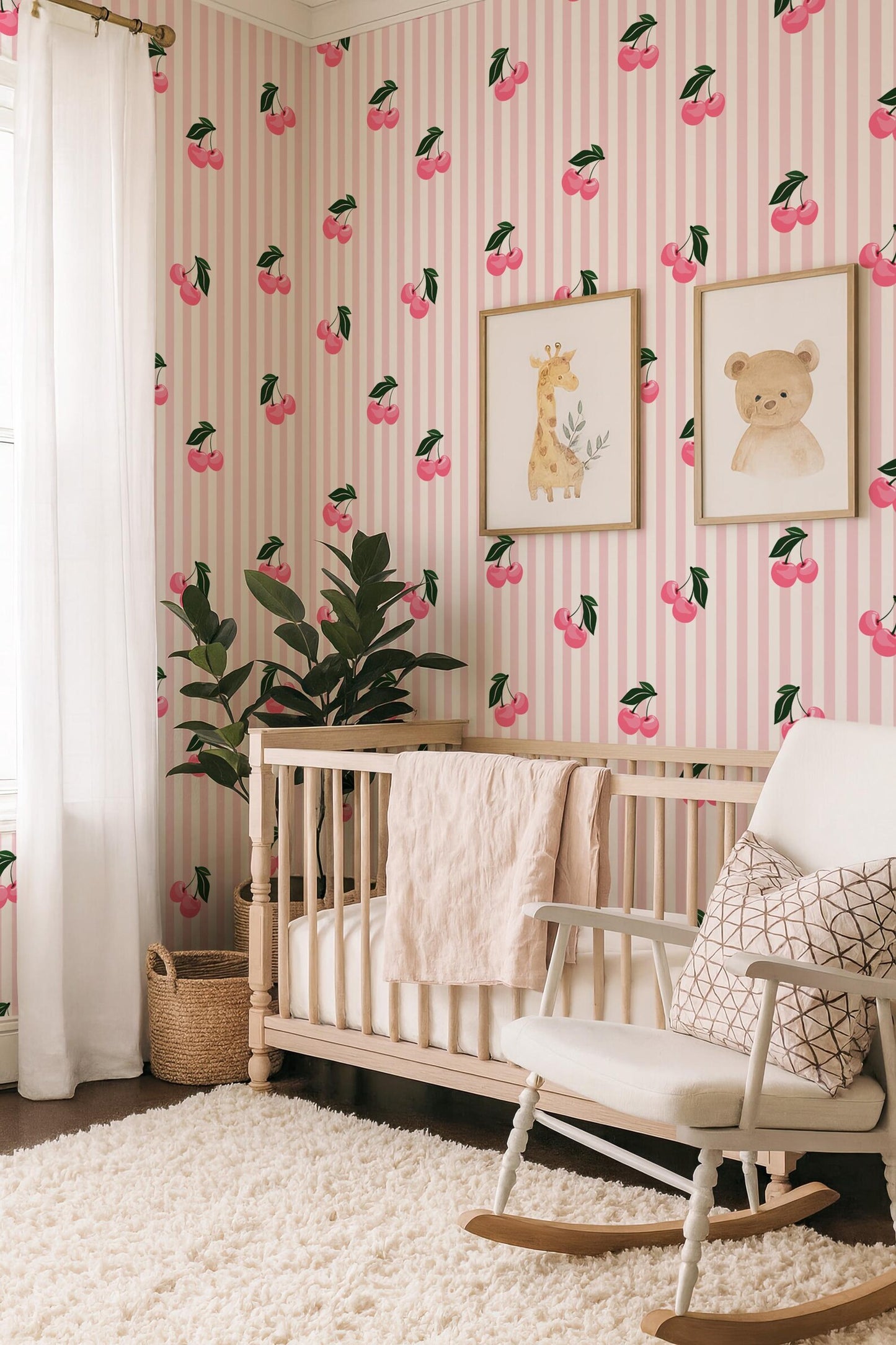 a nursery room with a pink and white striped wallpaper, a wooden crib, a white rocking chair, and two framed animal illustrations on the wall.
