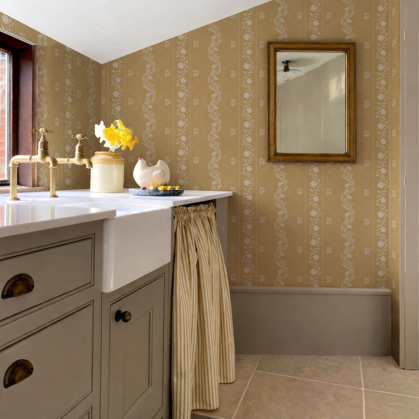 a bathroom with a sink, a mirror, and a window. The walls are covered in a floral wallpaper, and there is a curtain hanging from the window.