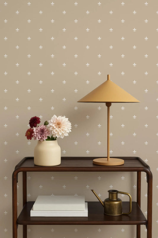 a wooden side table with a lamp, a vase with flowers, and a book on it. The table is set against a wall with a pattern of small white dots.