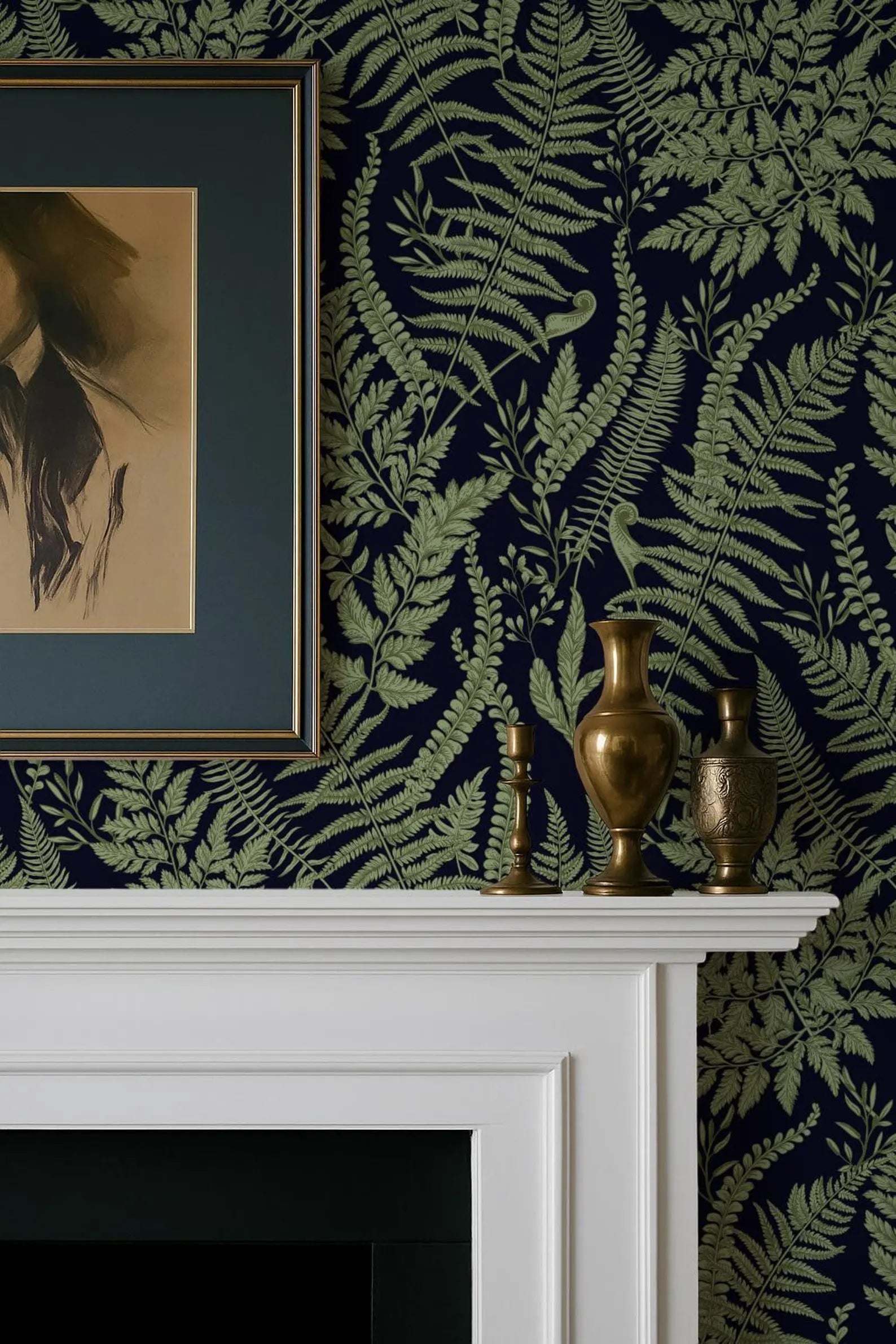 a fireplace mantel with a framed picture, two brass vases, and a framed artwork on a dark green wall with a fern pattern.