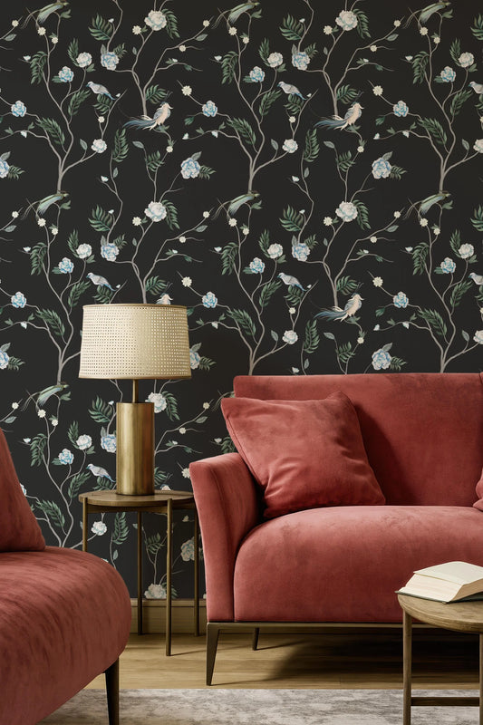 a living room with a red sofa, a gold side table with a lamp, and a black wall with a floral wallpaper.