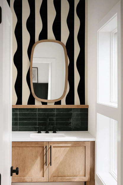 a bathroom with a white sink and a mirror above it, set against a black and white striped wall.