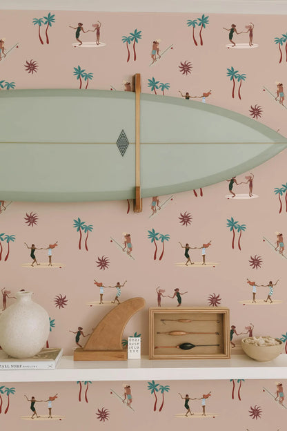 a wall with a surfboard, a wooden sculpture, and various other decorative items such as a vase and a bowl, all set against a background with a repeating pattern of palm trees and people surfing.