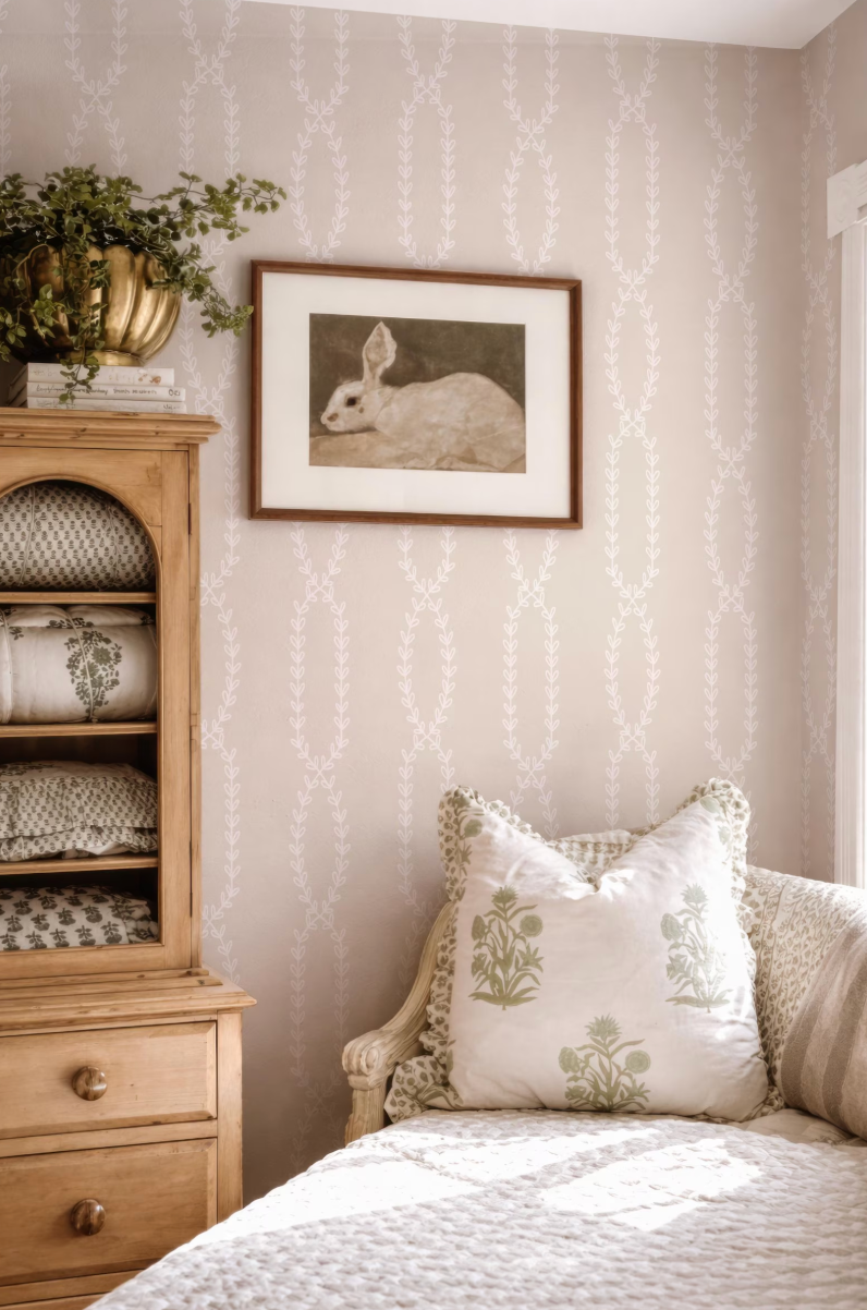 a cozy bedroom scene with a framed picture of a rabbit on the wall, a wooden dresser, a white sofa with patterned pillows, and a potted plant on top of the dresser.