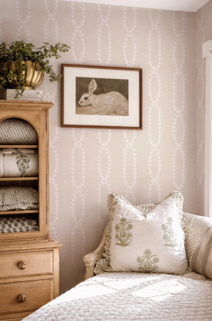 a cozy bedroom scene with a framed picture of a rabbit on the wall, a wooden dresser, a white sofa with patterned pillows, and a potted plant on top of the dresser.