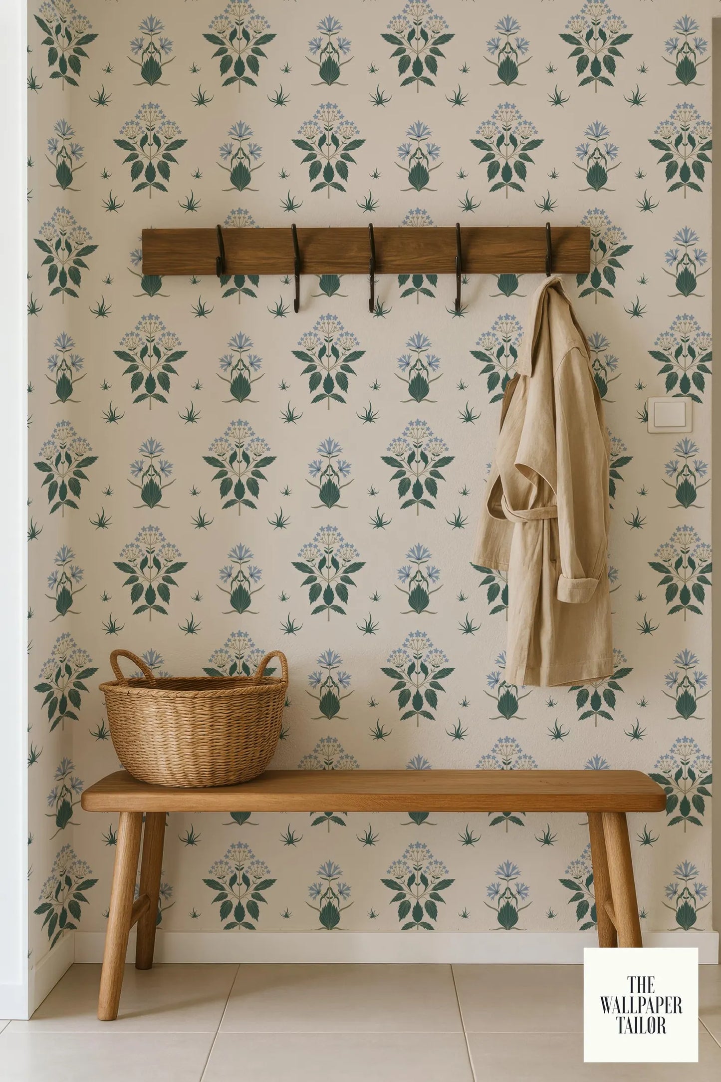 a wooden bench with a wicker basket on it, set against a wall with a repeating floral pattern. A coat is hanging on a wooden rack above the bench.
