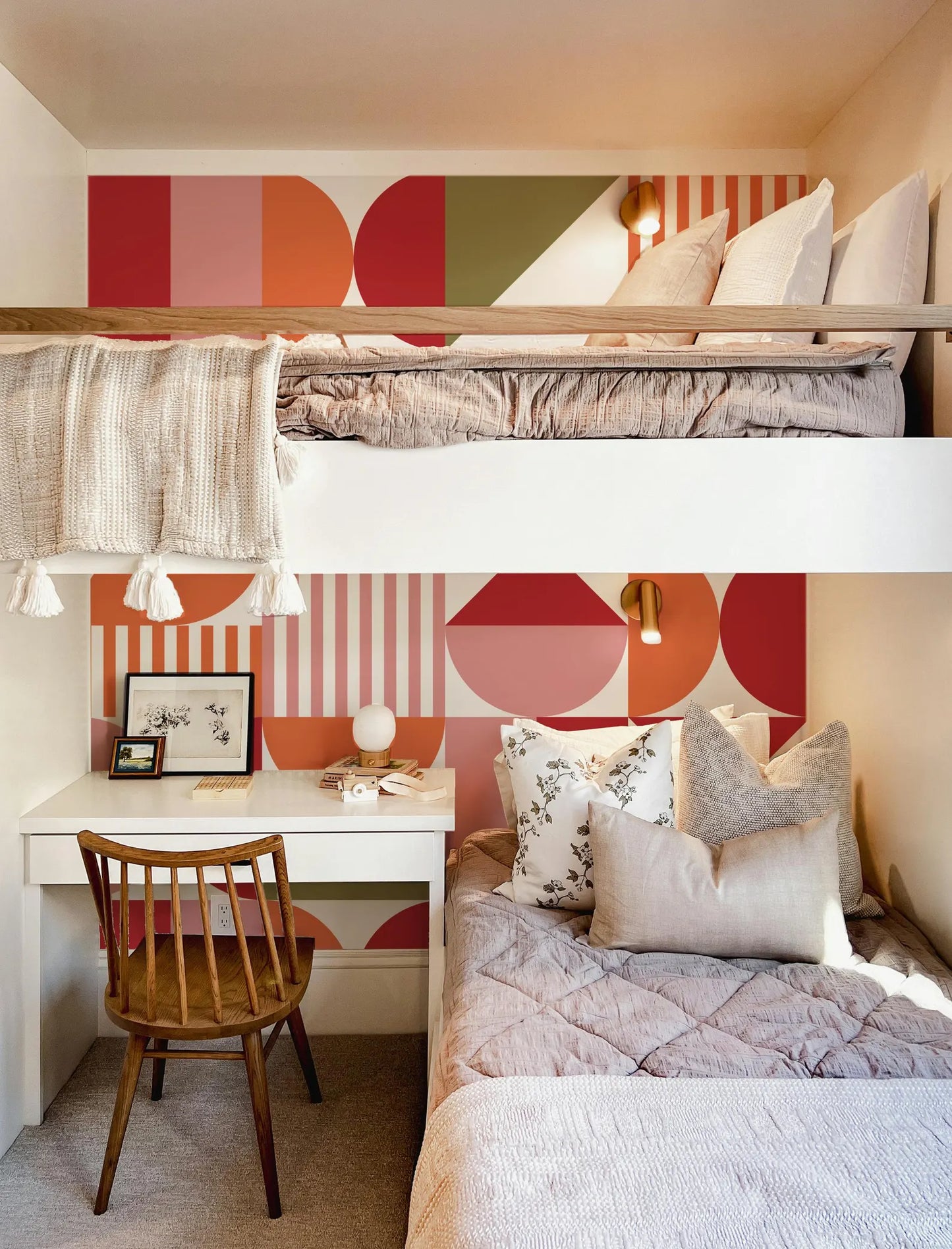 a cozy and stylishly decorated bedroom with a bunk bed, a desk, and a comfortable bed with decorative pillows.