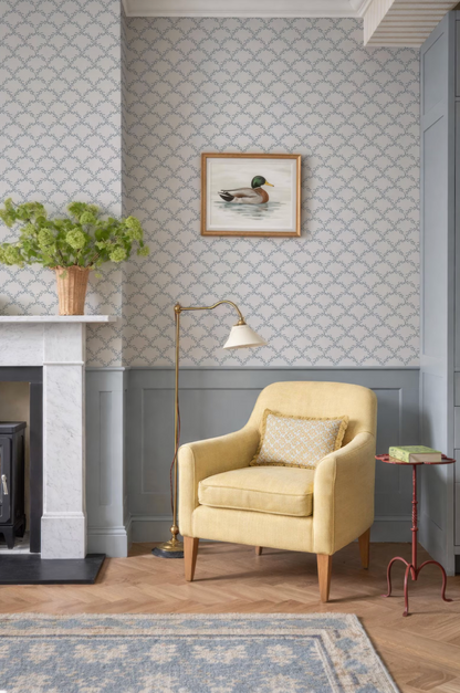a cozy living room with a yellow armchair, a fireplace, a framed picture of a duck, and a floor lamp.