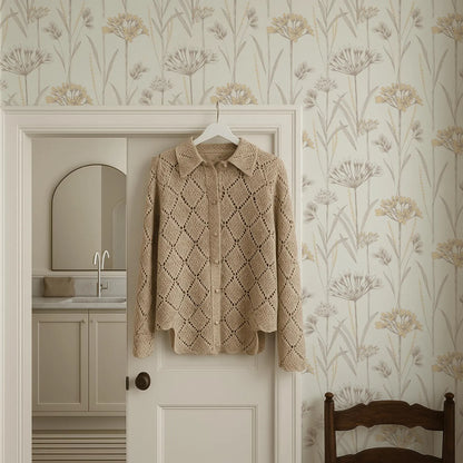 a cozy, beige knitted sweater hanging on a white door, with a wooden chair placed to the side. The room has a floral wallpaper, and a bathroom can be seen in the background.