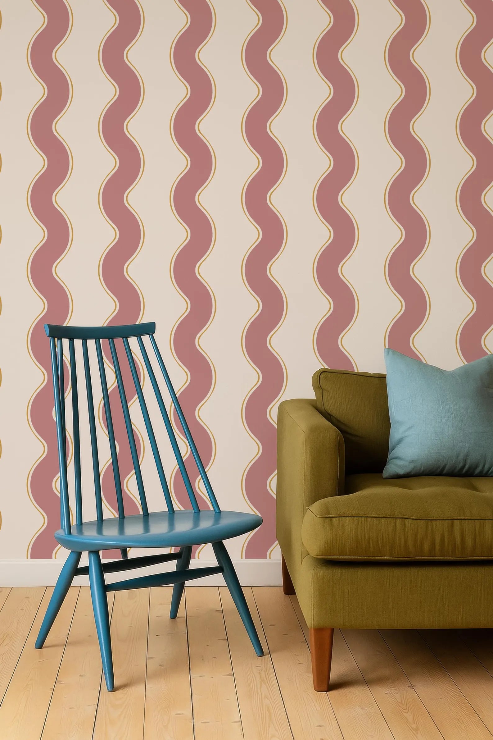 a blue chair and a green sofa against a wall with a repeating pattern of red and white wavy lines.