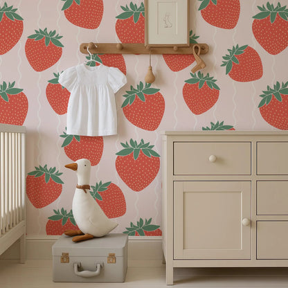 a nursery room with a white dresser, a stuffed duck, and a wallpapered wall with a strawberry pattern.