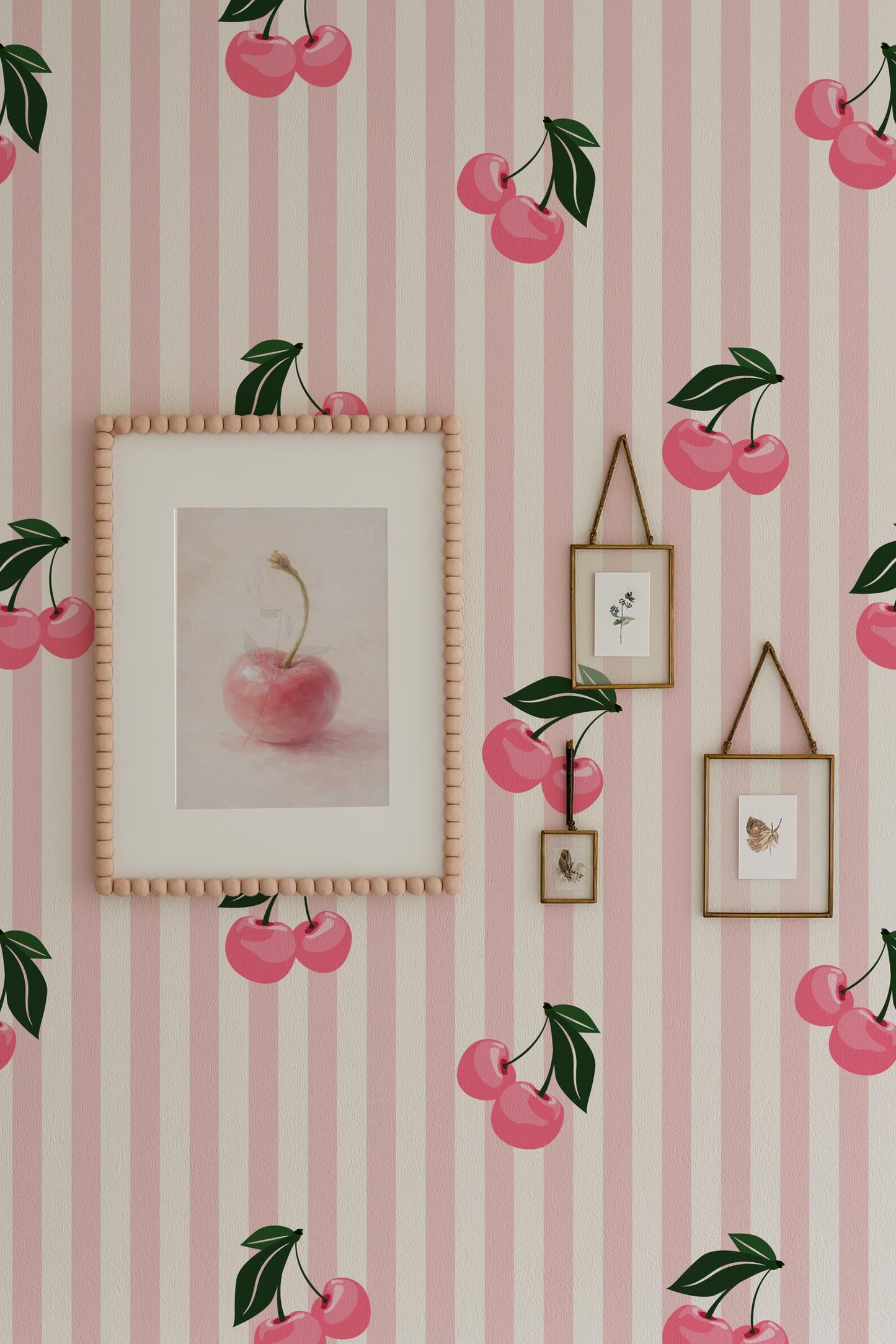 a wallpapered wall with a framed picture of a pink apple, two smaller framed pictures, and a framed picture of cherries. The wallpapered wall has a pink and white striped pattern, and the overall color scheme is predominantly pink and white.