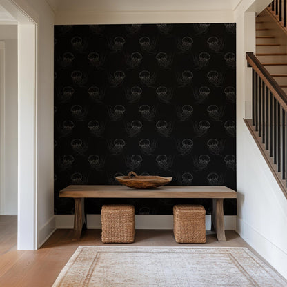 a modern interior design with a dark wall adorned with a repeating pattern of jellyfish or sea creatures. In front of the wall, there is a wooden table with two woven ottomans, creating a cozy seating area. The overall color scheme of the room is predominantly black and white, with the jellyfish pattern adding a touch of contrast.