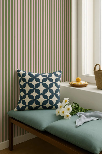 a cozy corner with a green bench, a blue and white patterned pillow, a basket of flowers, and a small wooden tray with an orange. The background has a striped pattern, and there is a window with white curtains.