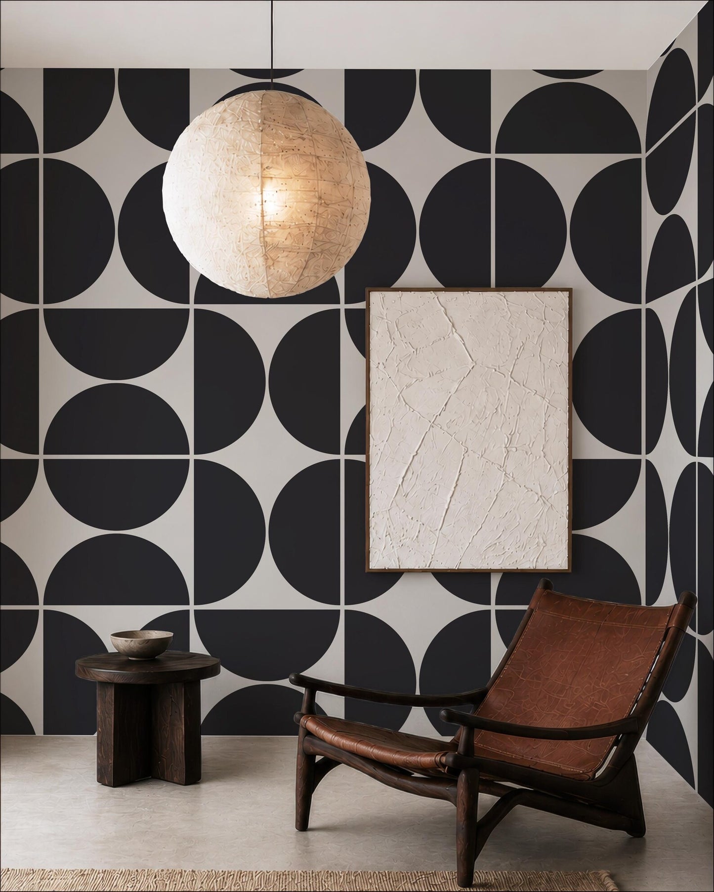 a modern living room with a black and white geometric patterned wall, a wooden chair, a round wooden table, and a large round light fixture hanging from the ceiling.