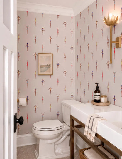 a bathroom with a white toilet, a sink, and a wallpapered wall with a repeating pattern of colorful figures.