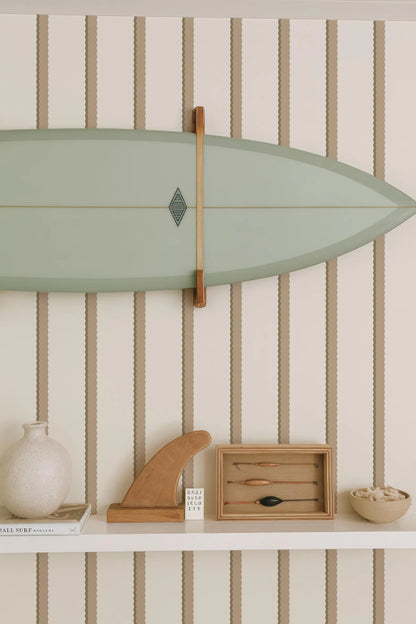 a shelf with various items, including a green surfboard, a wooden surfboard holder, a white vase, a wooden sculpture, and a small wooden box with a black object inside.