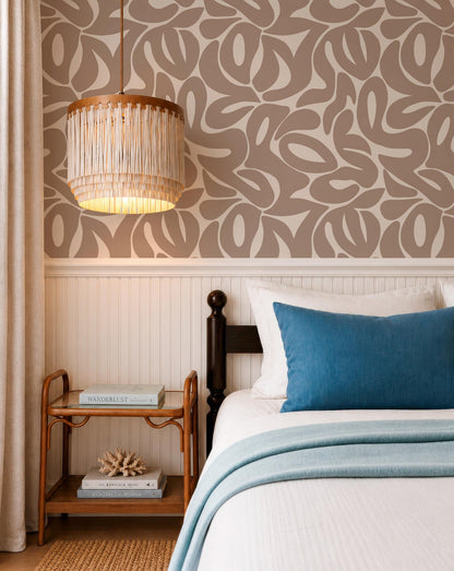 a cozy bedroom with a bed, a wooden nightstand, and a chandelier. The room has a neutral color scheme with a patterned wallpaper and a blue throw blanket on the bed.