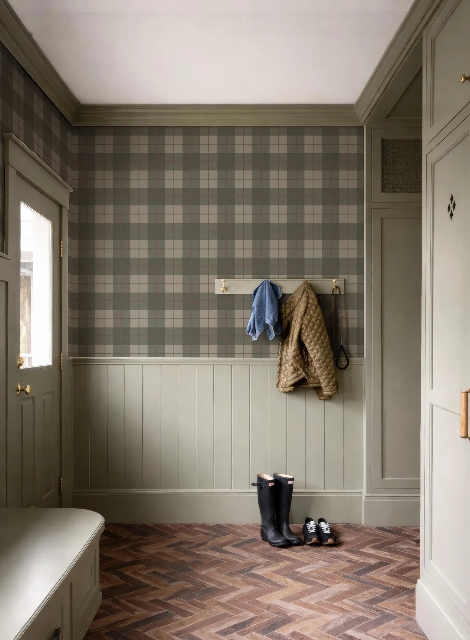 a hallway with a checkered wallpaper, a coat rack with a jacket and a pair of boots, and a bench.