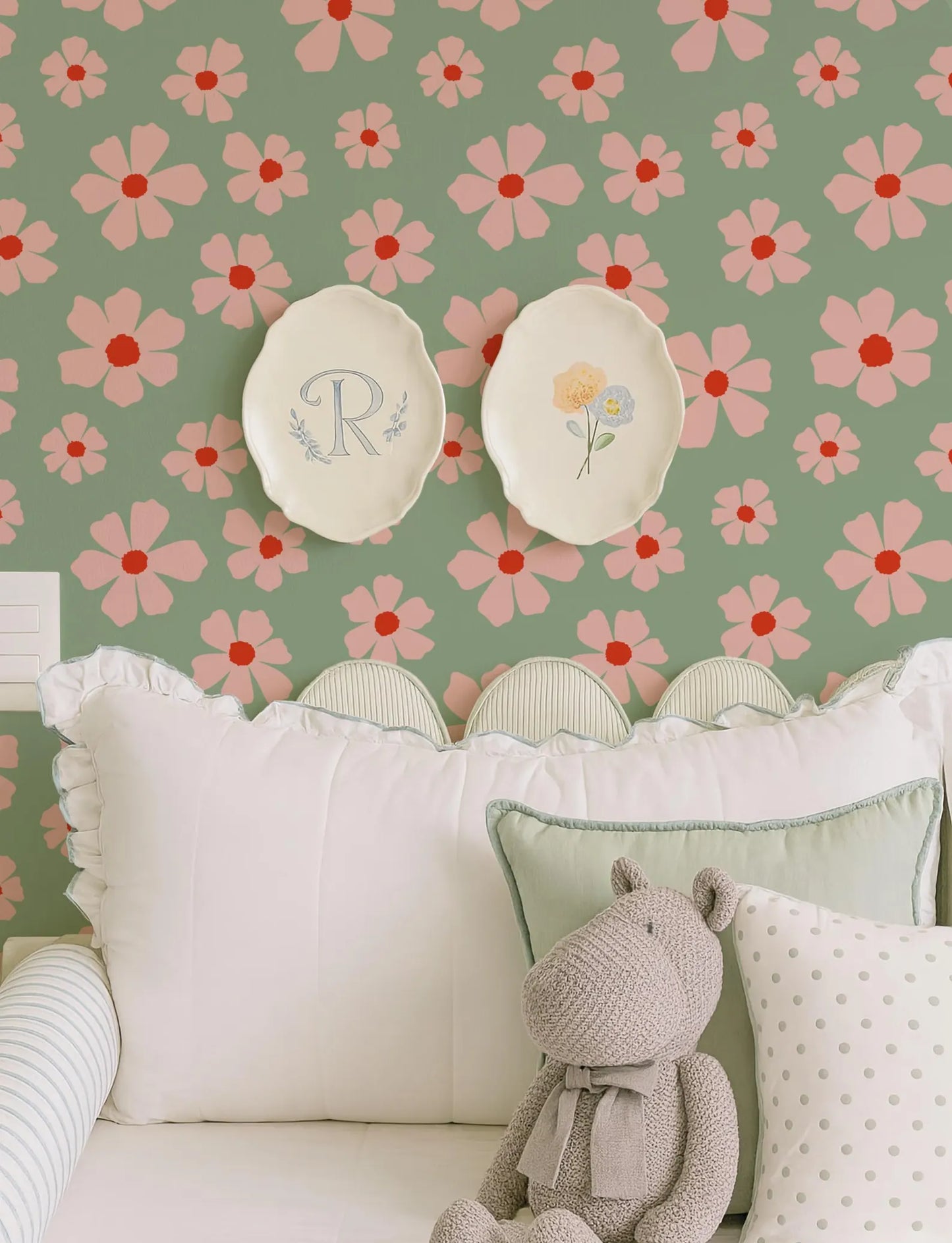 a cozy and charming bedroom scene with a floral wallpaper, two white plates with flowers, and a stuffed animal on a bed.