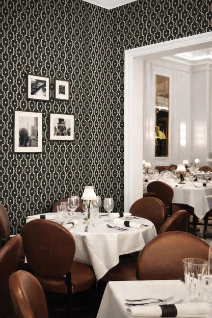 a dining room with a black and white patterned wallpaper, a table set with white tablecloths, and a variety of chairs surrounding the table.