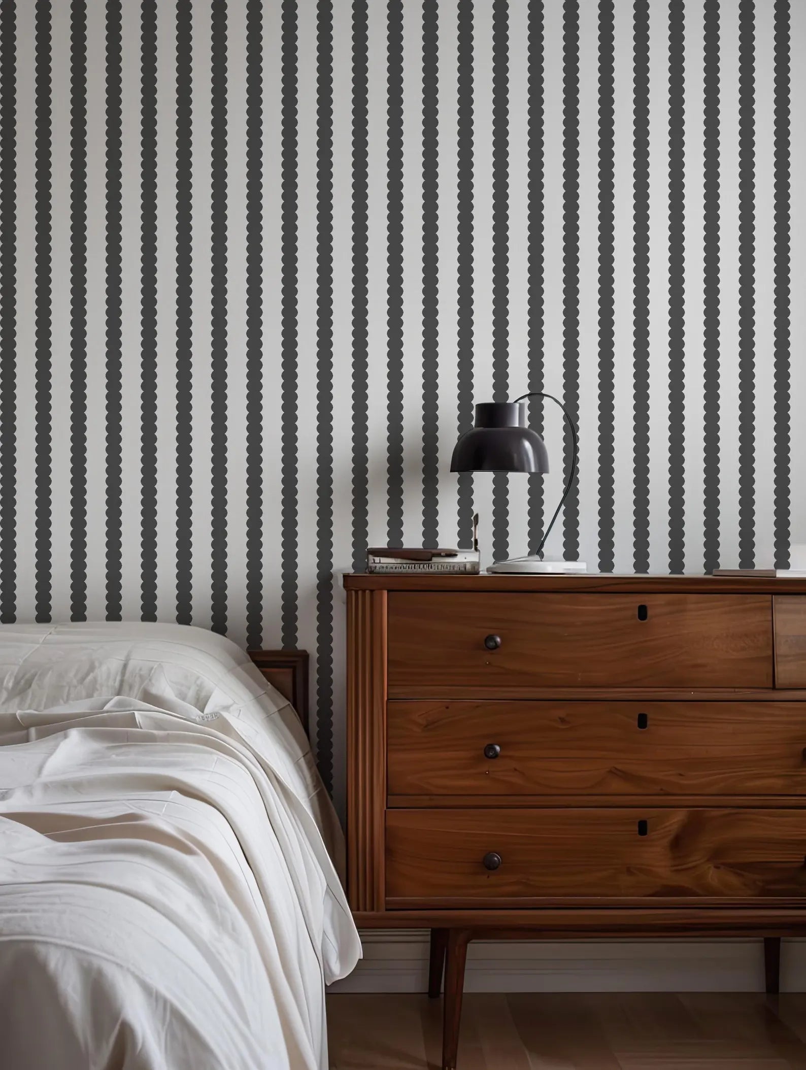 a bedroom with a bed, a wooden dresser, and a striped wallpaper.