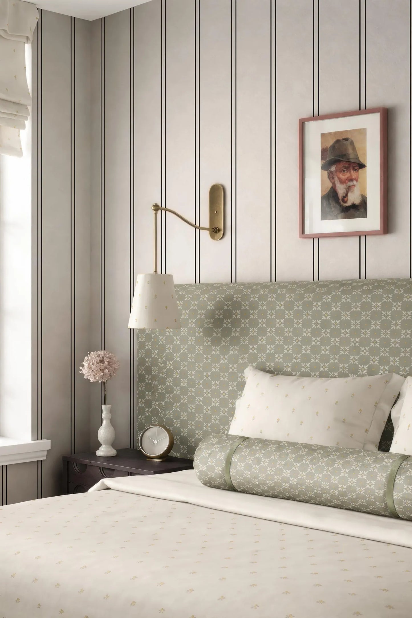 a cozy bedroom with a bed, a nightstand, and a framed picture on the wall. The bed has a green and white patterned headboard, and the room has a neutral color scheme with gray and white walls.