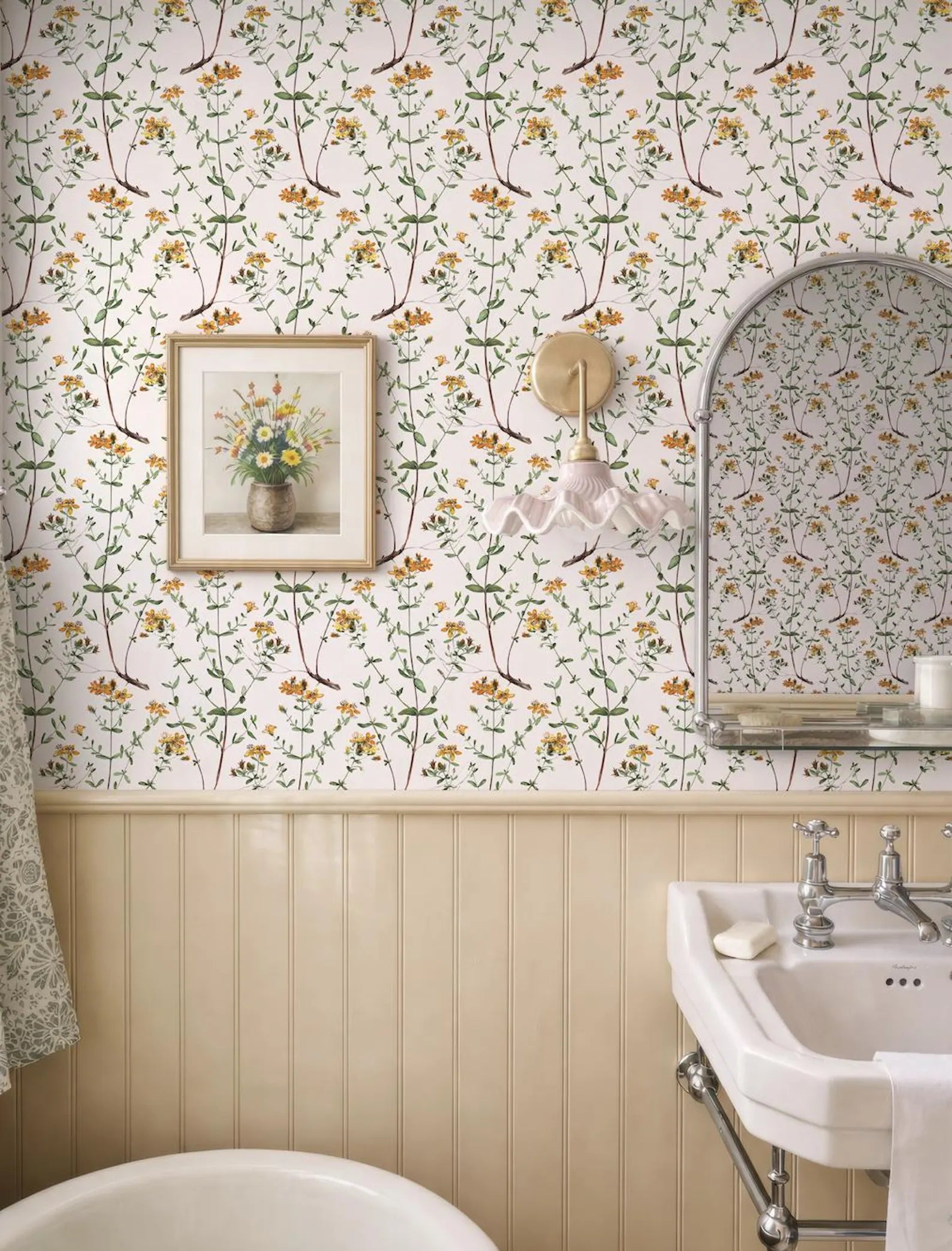 a bathroom with a floral wallpaper, a white sink, a framed picture of flowers, and a mirror above the sink.