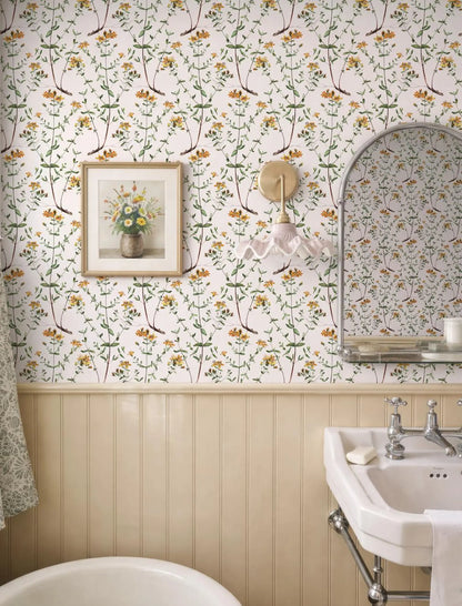 a bathroom with a floral wallpaper, a white sink, a framed picture of flowers, and a mirror above the sink.
